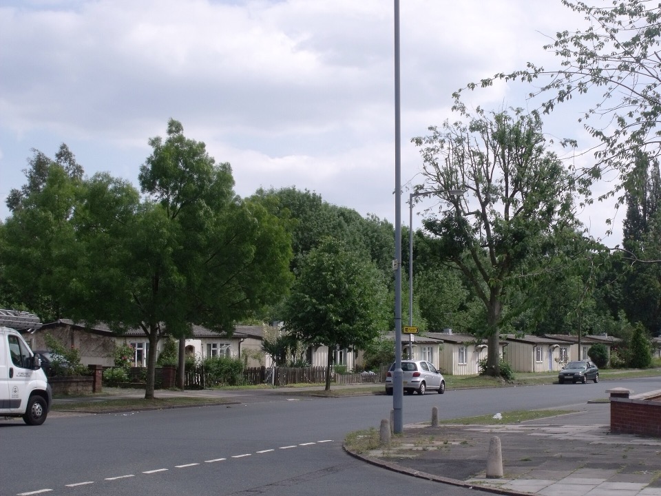 Post-war prefabricated bungalows on Wake Green Road in Moseley, Birmingham, behind front gardens and trees